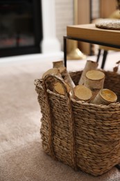 Photo of Firewood in wicker basket in room, closeup view