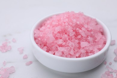 Photo of Plate with pink sea salt on white marble table, closeup