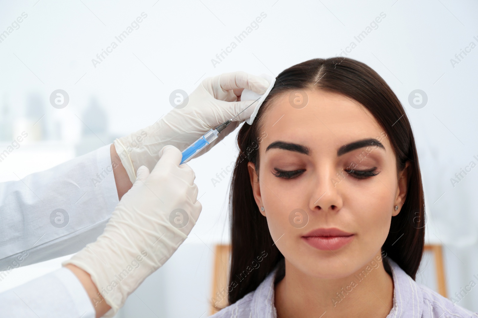 Photo of Young woman with hair loss problem receiving injection in salon