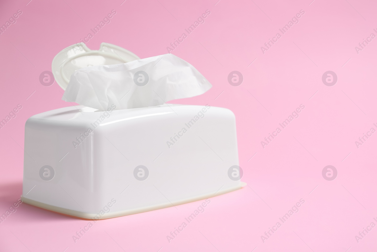 Photo of Holder with paper tissues on pink background