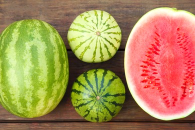 Photo of Different cut and whole ripe watermelons on wooden table, flat lay