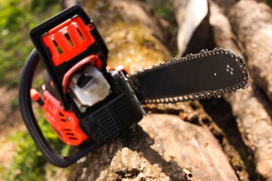 Photo of One modern saw on wooden log outdoors