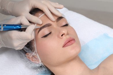 Photo of Young woman during procedure of permanent eyebrow makeup in beauty salon, closeup