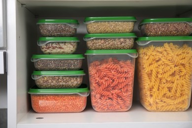 Plastic containers filled with food products in kitchen cabinet, closeup