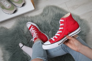 Photo of Woman with new stylish red sneakers indoors, top view