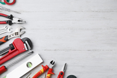 Photo of Flat lay composition with different construction tools on white wooden background. Space for text