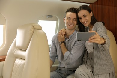 Photo of Lovely young couple taking selfie in airplane during flight