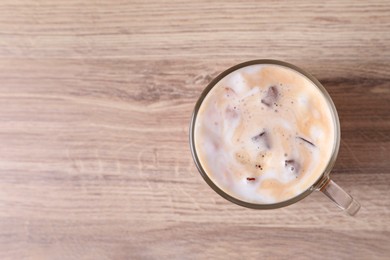 Photo of Cup of fresh iced coffee on wooden table, top view. Space for text