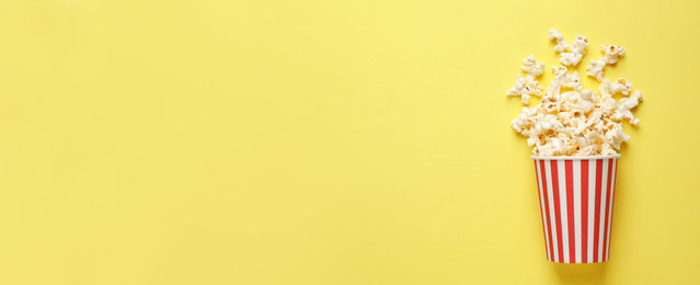 Image of Delicious popcorn and space for text on yellow background, top view. Banner design
