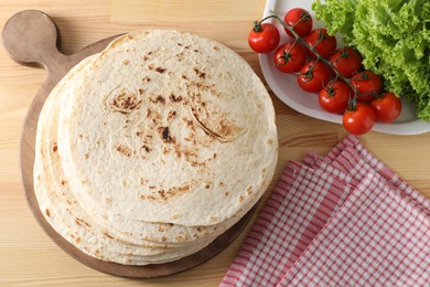 Many tasty homemade tortillas and products on wooden table, flat lay