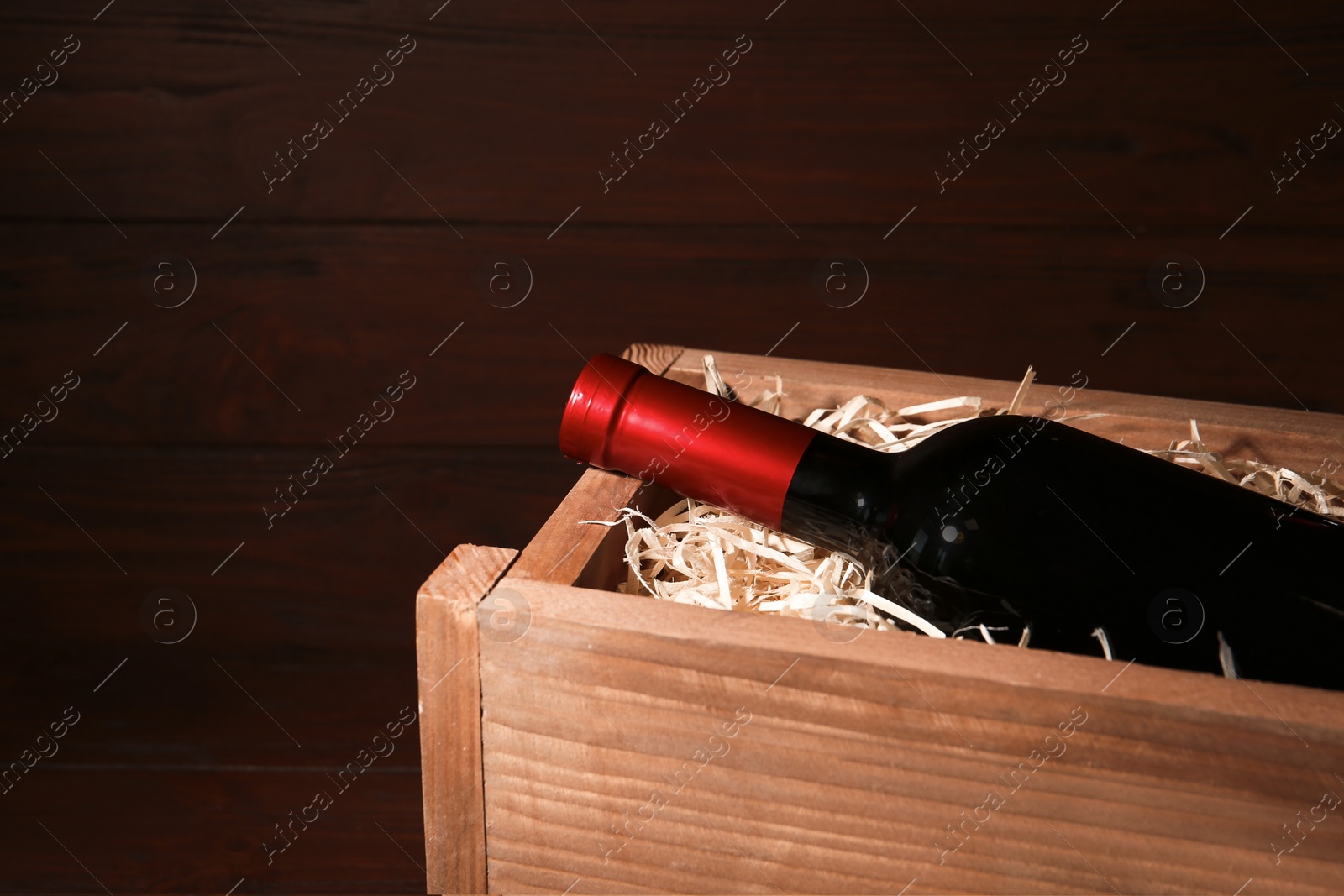 Photo of Open wooden crate with bottle of wine, space for text