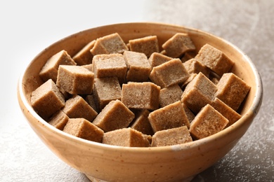 Bowl with cubes of brown sugar on table, closeup