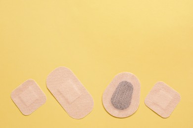 Photo of Different contraceptive patches on yellow background, flat lay. Space for text