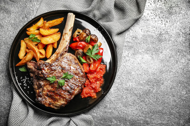 Photo of Delicious grilled ribeye served on grey table, flat lay. Space for text