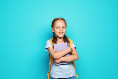 Photo of Little school child with backpack and copybook on color background