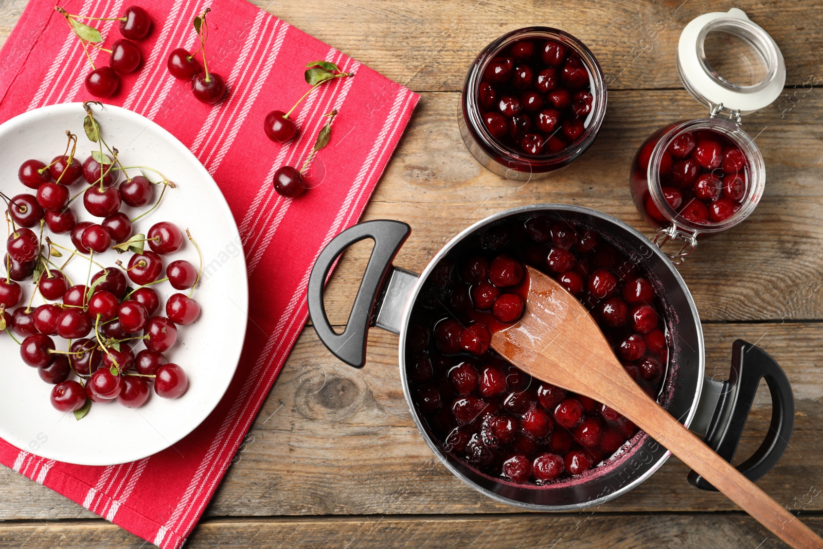 Photo of Pot with cherries in sugar syrup and fresh berries on wooden table, flat lay. Making delicious jam