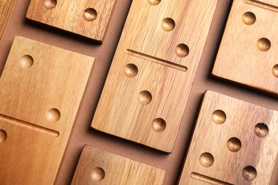 Photo of Set of wooden domino tiles on brown background, flat lay