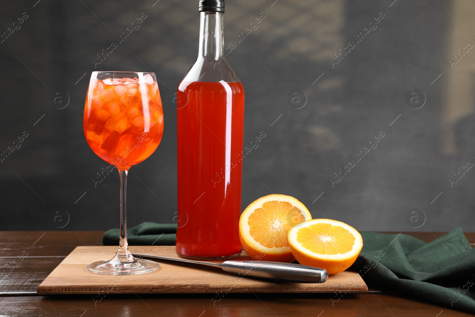 Photo of Aperol spritz cocktail and ice cubes in glass and bottle on wooden table