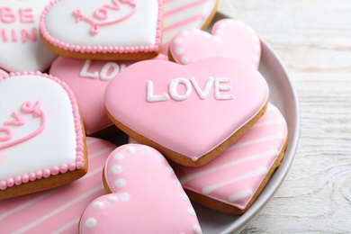 Photo of Decorated heart shaped cookies on white wooden table, closeup. Valentine's day treat