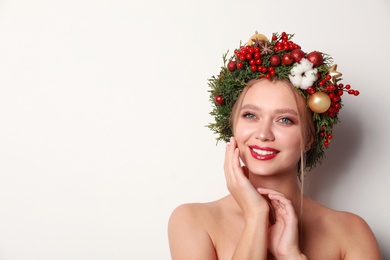 Photo of Beautiful young woman wearing Christmas wreath on white background. Space for text