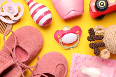 Photo of Flat lay composition with pacifiers and other baby stuff on yellow background