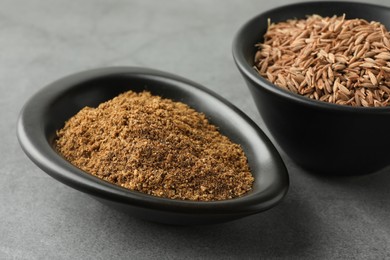 Photo of Caraway (Persian cumin) powder and dry seeds on gray table, closeup