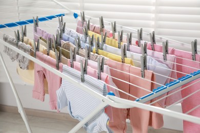 Clean laundry hanging on drying rack indoors