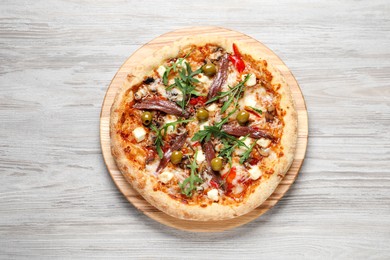 Tasty pizza with anchovies, arugula and olives on grey wooden table, top view