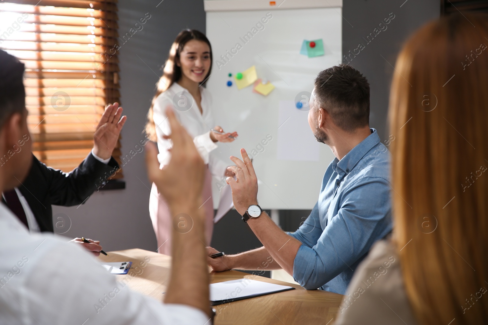 Photo of People raising hands to ask questions at seminar in office