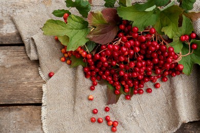 Branch of viburnum with ripe berries on wooden table, flat lay