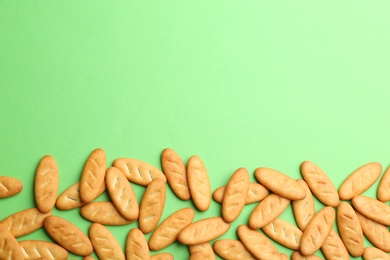 Delicious crackers on light green background, flat lay. Space for text