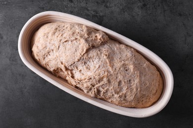 Photo of Fresh sourdough in proofing basket on grey table, top view