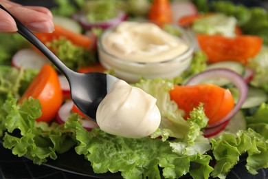 Photo of Woman dressing delicious vegetable salad with mayonnaise, closeup