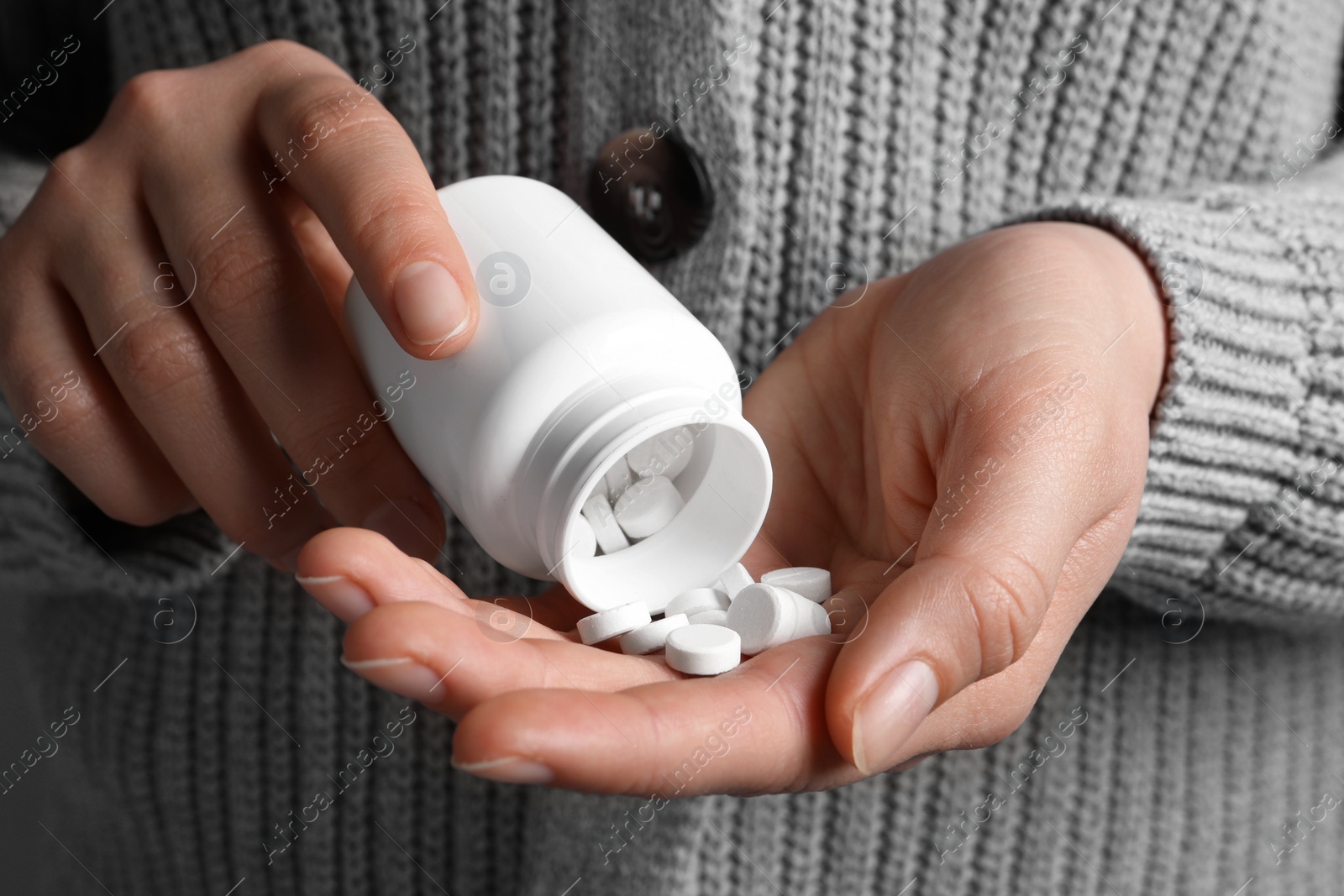 Photo of Woman pouring pills from bottle, closeup view