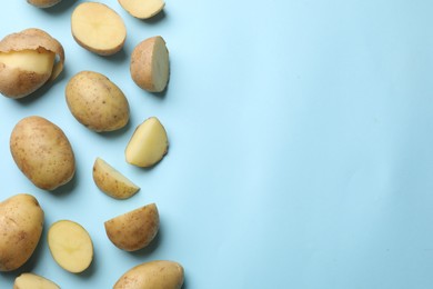 Photo of Fresh raw potatoes on light blue background, flat lay. Space for text