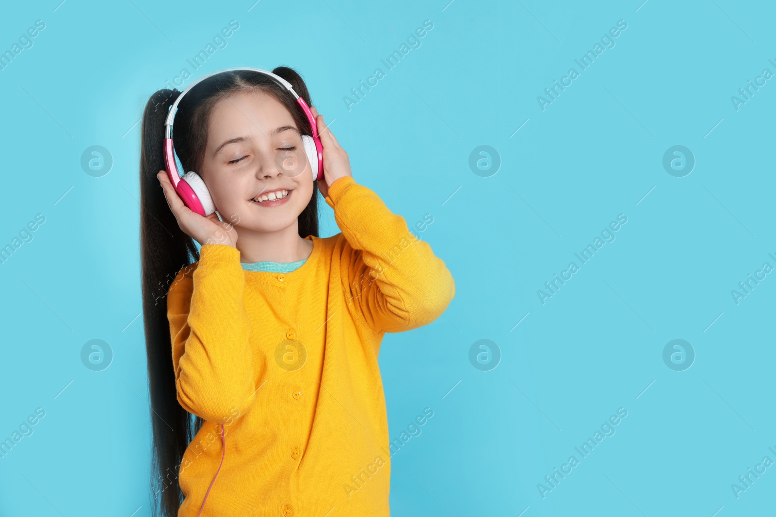 Photo of Cute girl enjoying music in headphones on color background. Space for text