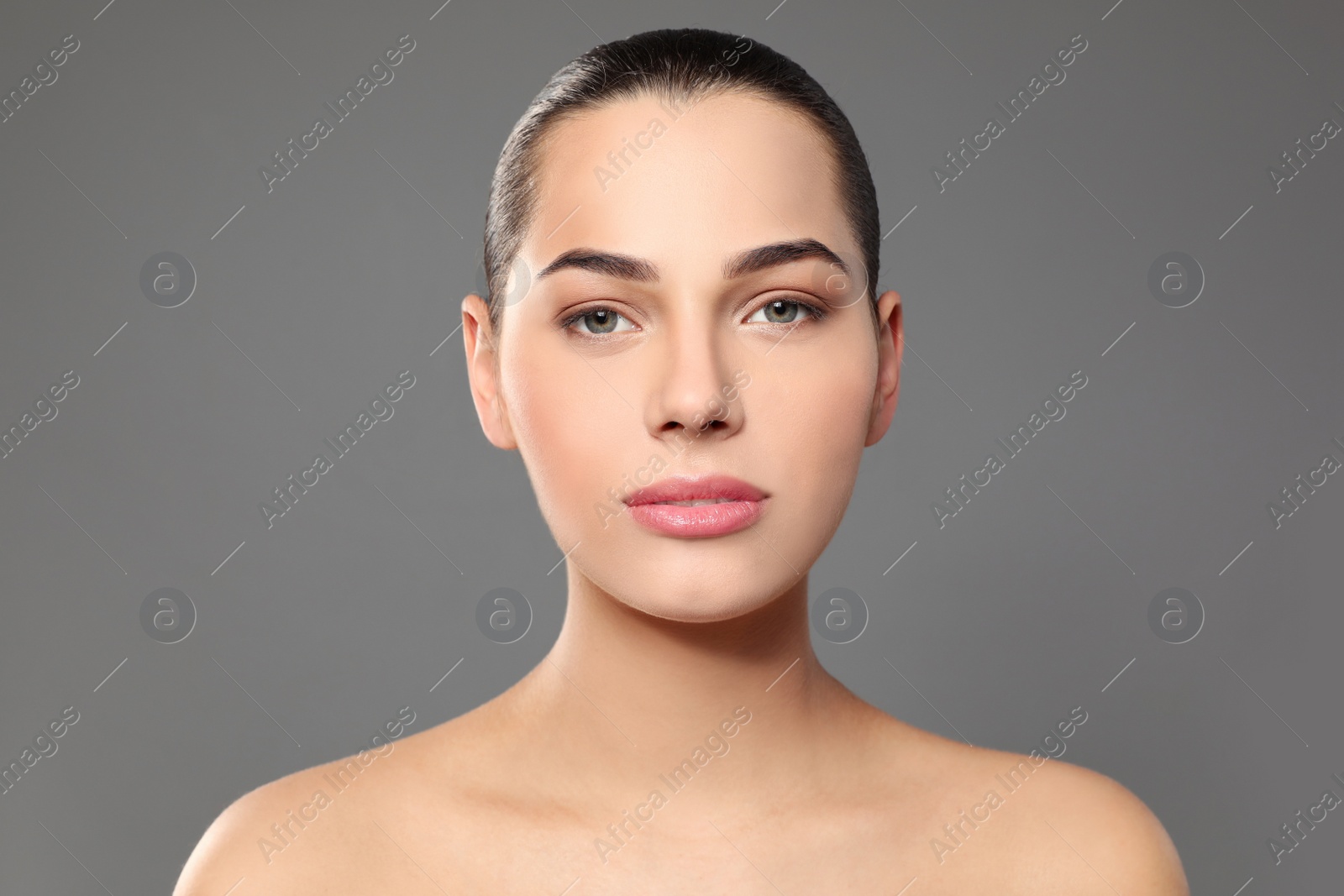 Photo of Portrait of young woman with beautiful face and natural makeup on color background