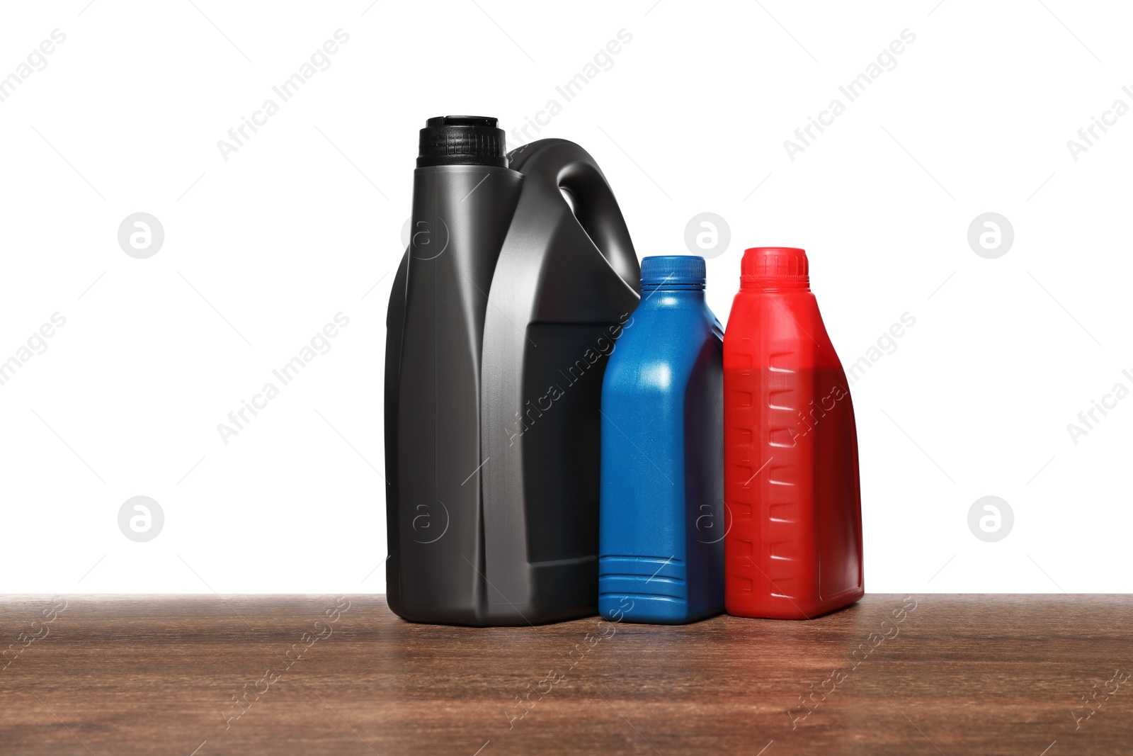 Photo of Motor oil in different containers on wooden table against white background