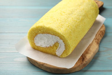 Delicious cake roll on light blue wooden table, closeup