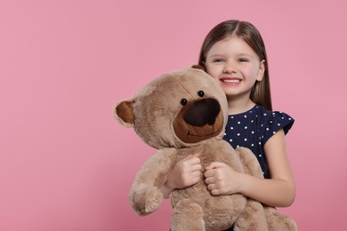 Cute little girl with teddy bear on pink background. Space for text