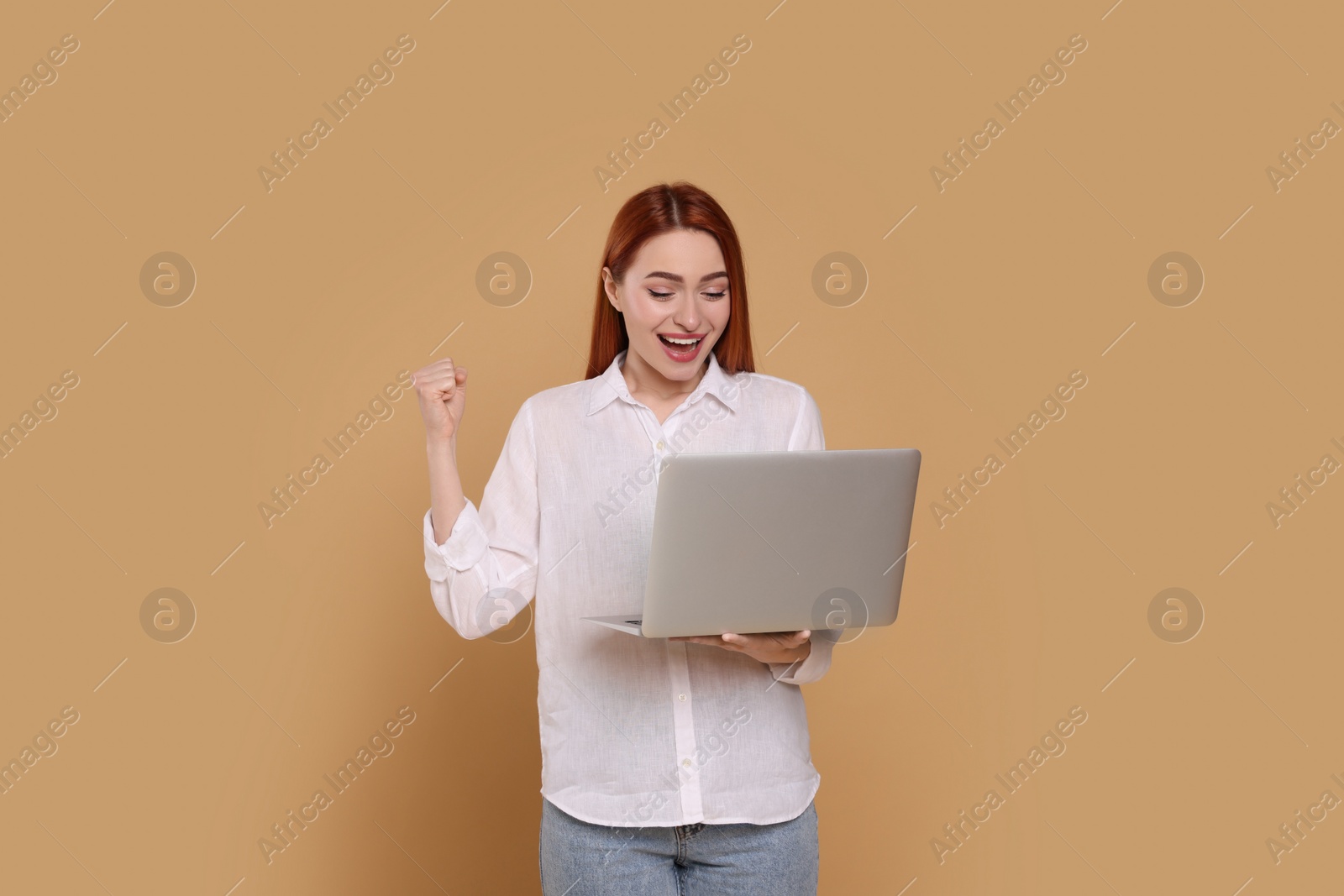 Photo of Happy young woman with laptop on beige background