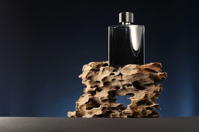 Photo of Luxury men`s perfume in bottle on grey table against dark background, space for text