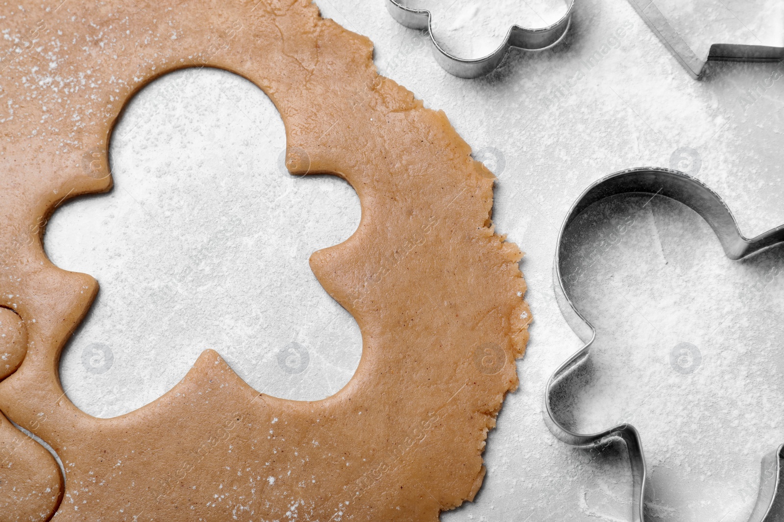 Photo of Making homemade Christmas cookies. Dough for gingerbread man and cutters on light grey table, flat lay