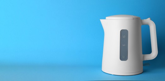 Photo of Modern electric kettle on light blue background, space for text