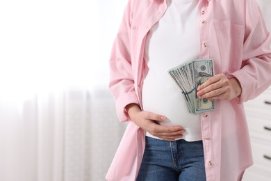 Photo of Surrogate mother. Pregnant woman with dollar banknotes indoors, closeup. Space for text