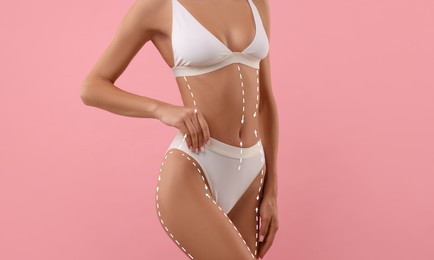 Image of Woman showing her beautiful figure on pink background, closeup. Cosmetic treatment lines on her body