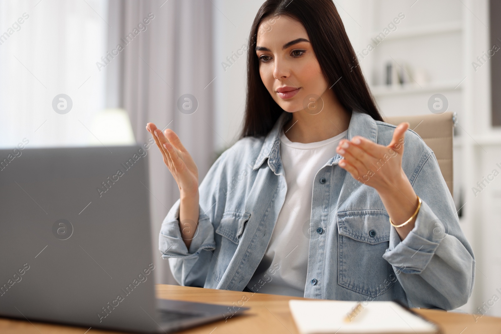 Photo of Young woman using video chat during webinar at table in room