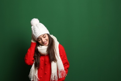 Young woman wearing warm clothes on color background, space for text. Winter season