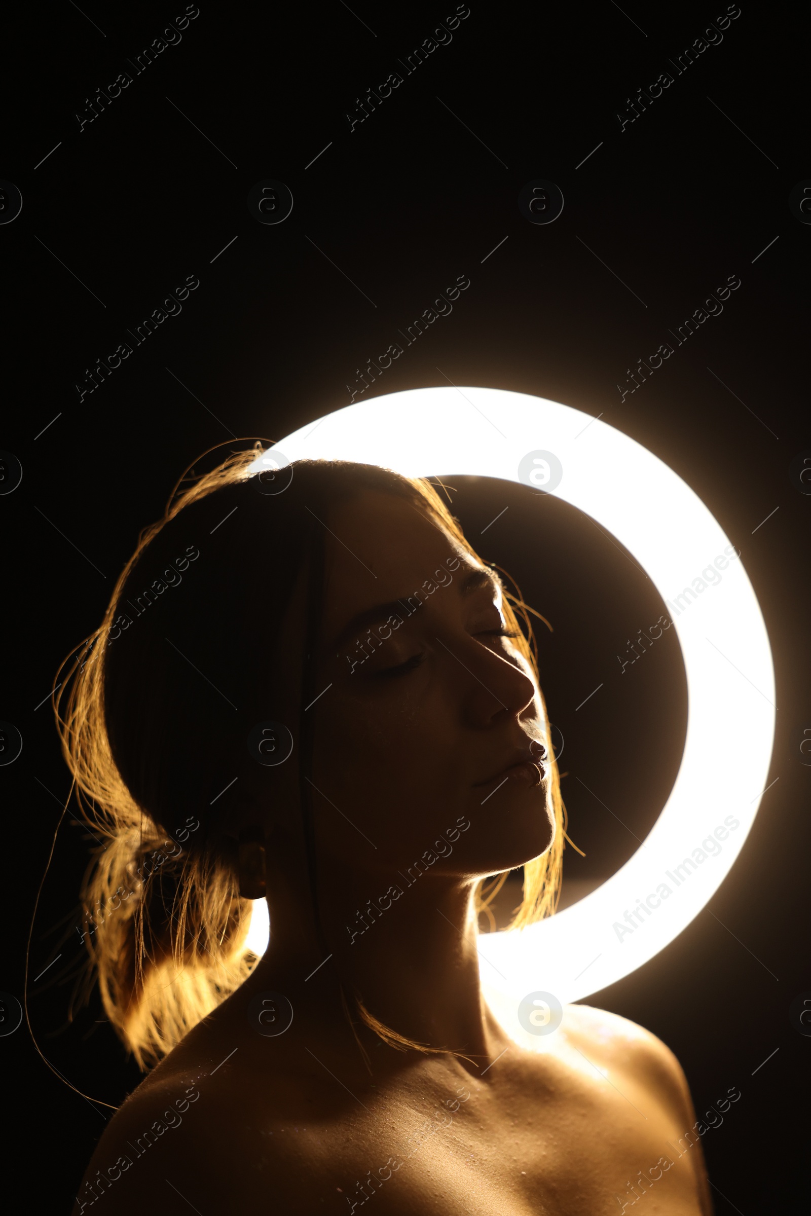 Photo of Beautiful woman and ring lamp in darkness