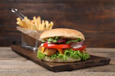 Photo of Delicious tofu burger served with french fries on wooden table